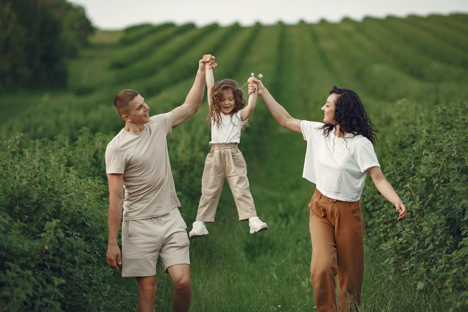 parents holding their daughters hands and putting her in the air