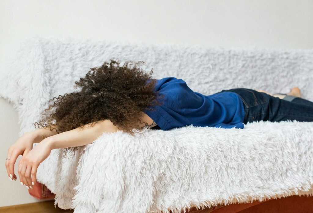 Emotionally Present Parenting Even When You’re Exhausted woman wearing blue shirt lying on white couch