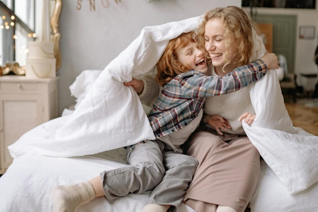 Why Self-Compassion for Parents Is the Key to Better Parenting a mother and daughter smiling while under a blanket