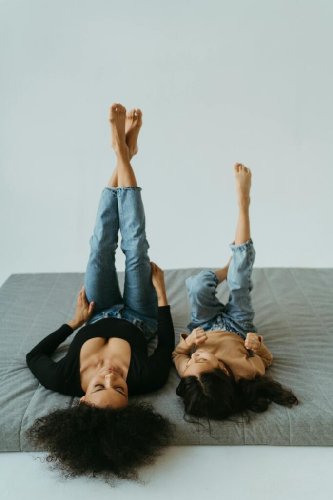 Why Self-Compassion for Parents Is the Key to Better Parenting mother and daughter lying on the bed with legs up